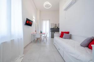 a white living room with a white couch and red pillows at PALAZZO DUCALE - Romantico appartamento in centro in Modena