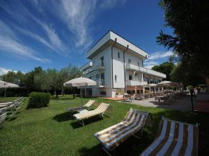 a building with lounge chairs and umbrellas in the grass at Hotel Saviola in Sirmione