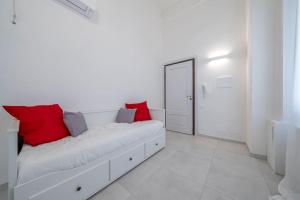 a white couch with red pillows in a white room at PALAZZO DUCALE - Romantico appartamento in centro in Modena