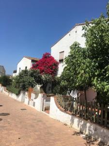 una recinzione accanto a un edificio bianco con fiori rossi di Casa en Palamós (Costa Brava). Unifamiliar, 3 BDRM, 6 Pers, Garage a Palamós
