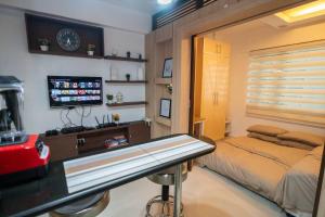 een kamer met een bed, een bureau en een televisie bij A2J Executive Studio Near Venice Mall BGC Taguig in Manilla