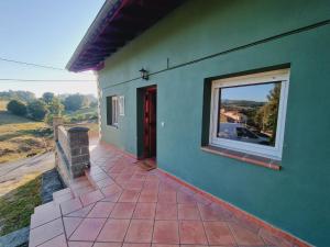 ein grünes Haus mit einem Fenster und einer Terrasse in der Unterkunft Casa Rural Villapresente in Reocín