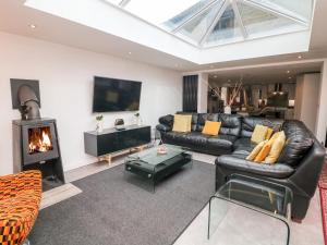 a living room with a black leather couch and a fireplace at Carr House Farm in Glossop