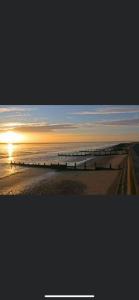 a view of a beach with a pier at sunset at A new built brick chalet in Leysdown-on-Sea
