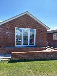 a red brick house with a window and steps at A new built brick chalet in Leysdown-on-Sea