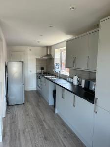 a kitchen with white cabinets and a stainless steel refrigerator at A new built brick chalet in Leysdown-on-Sea