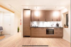 a kitchen with wooden cabinets and a stove top oven at Aurora and midnight sun in Tromsø