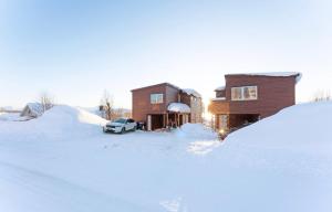 a car parked in front of a house covered in snow at Aurora and midnight sun in Tromsø