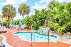 una piscina en un patio con palmeras en Sand Pebble Resort en St Pete Beach