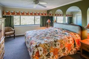 a bedroom with a bed with a floral bedspread and windows at Sand Pebble Resort in St Pete Beach