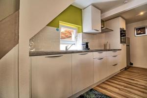eine Küche mit weißen Schränken und einer grünen Wand in der Unterkunft Logement CHEZ ANTHONE - Proche Obernai, logement pour 1 à 5 personnes in Bernardswiller