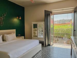 1 dormitorio con 1 cama grande y balcón en Hotel Del Portal San Miguel de Allende, en San Miguel de Allende