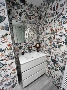 uma casa de banho com um lavatório branco e papel de parede floral em LA CASA DE LA CÁMARA em Avilés