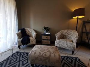 two chairs and a ottoman in a living room at Private Apartment for business and leisure Pretoria East in Pretoria