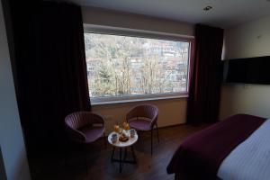 1 Schlafzimmer mit einem Bett, 2 Stühlen, einem Tisch und einem Fenster in der Unterkunft Monarch Hotel in Prizren