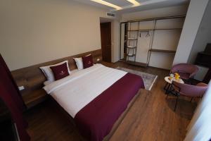 a bedroom with a large bed and a chair at Monarch Hotel in Prizren