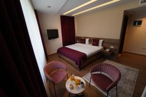 a hotel room with a bed and a table and chairs at Monarch Hotel in Prizren