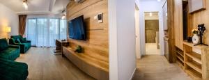a living room with a couch and a tv on a wall at Green Luxury Apartment Lake On in Mamaia