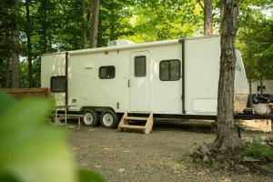 een witte trailer geparkeerd naast een boom bij Grotto Getaway in Miller Lake