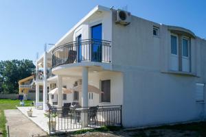 ein weißes Apartmenthaus mit einem Balkon und Sonnenschirmen in der Unterkunft Aida Apartments in Ulcinj