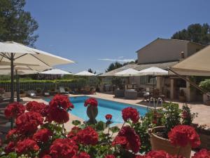 a swimming pool with red flowers and umbrellas at La Bégude Du Pascouren in Fayence
