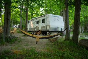 een hangmat aangesloten op een caravan in een bos bij Grotto Getaway in Miller Lake