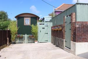 ein grünes Haus mit einer Tür und einem Zaun in der Unterkunft Little Worsley and The Shepherds Hut in Ventnor
