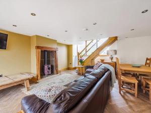 a living room with a leather couch and a table at The Barn in Holmfirth