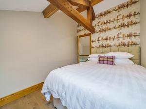 a bedroom with a white bed and a wall at The Barn in Holmfirth