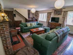 un soggiorno con divani verdi e camino di Primrose Spinney a Ringwood
