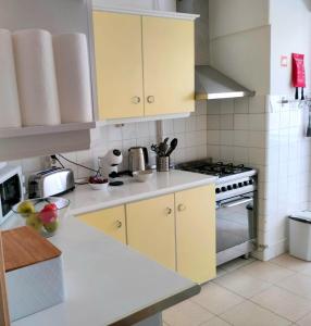 a kitchen with yellow cabinets and a stove at Figueira Family Apartment in Figueira da Foz