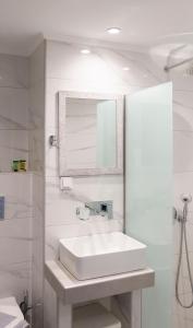 een witte badkamer met een wastafel en een spiegel bij Gorgona Hotel in Amoudara Herakliou