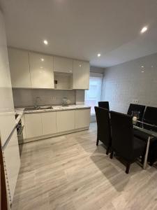 a kitchen with white cabinets and a table and chairs at LA CASA DEL MUELLE in Avilés