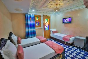 a room with two beds and a tv in it at Hotel & Ryad DALILA in Fès