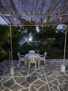 um pátio com uma mesa e cadeiras sob uma pérgola em Serenita verde Apartment em Poros