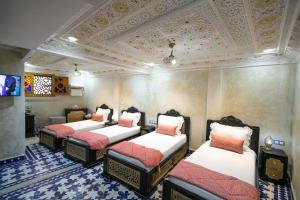 três camas num quarto com tecto em caixote em Hotel & Ryad DALILA em Fez