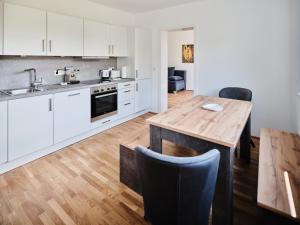 cocina con armarios blancos y mesa de madera en MySchönbrunn Apartments, en Viena