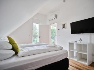 a white bedroom with a bed and a flat screen tv at MySchönbrunn Apartments in Vienna
