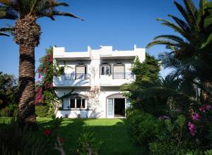 a white house with a palm tree in front of it at Gorgona Hotel in Amoudara Herakliou