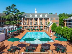 an outdoor pool with tables and green umbrellas in front of a building at Westgate Historic Williamsburg Resort in Williamsburg