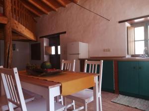 uma cozinha com uma mesa de madeira com cadeiras e um balcão em Monte Alentejano ideal para relaxar na natureza em São Teotónio