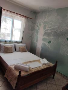 a bedroom with a bed with a tree mural on the wall at Kea Guesthouse in Ioulida