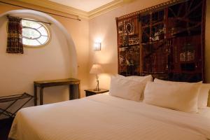 a bedroom with a large white bed with a window at Casa Quetzal in San Miguel de Allende