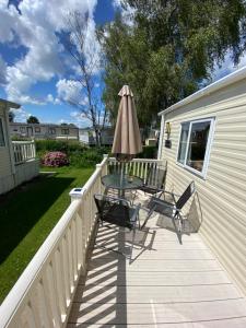 a deck with an umbrella and a table and chairs at Summer Breeze-Hoburne Cotswolds in South Cerney