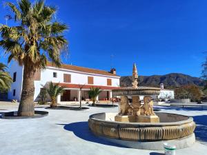 a fountain in a courtyard with a palm tree and a building at Finca El Espilo in Lúcar