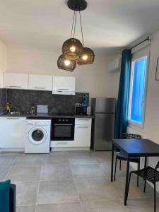 a kitchen with white appliances and a table and a dining room at Le Berlioz-Studio-Clim-Wifi-Balcon in Béziers