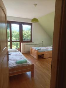 a bedroom with two beds and a large window at Domek Nad Dunajcem Liptak in Tylmanowa