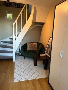 a living room with a green chair and stairs at The View Guesthouse at Ekeberg -10 min by tram to Oslo S in Oslo