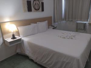 Hotel Champs Dumont في ماكاي: سرير أبيض كبير في غرفة الفندق مع مصباح