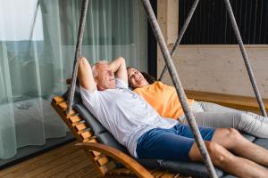 two people laying on a porch swing at Stock & Stein Lodges in Bad Gleichenberg